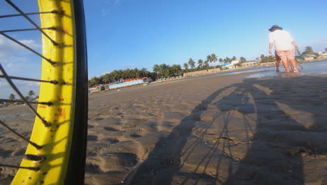 andar en bicicleta a toda velocidad en una playa, conocer gente pescando, vista en primera persona a nivel del suelo