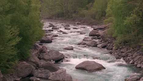 looking upstream at a clear blue river full of water and rocks as it streams down through the wilderness