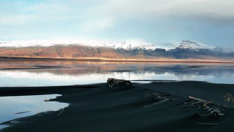 remains of shipwreck covered with black sand with scenic mountains views in iceland