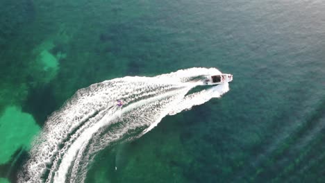 birds eye aerial of tubing behind pleasurecraft in clear green water