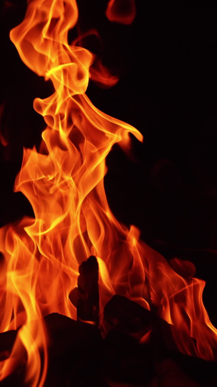 Legnetti che bruciano nel falò. Bellissima vista rilassante di un fuoco che arde di notte. Video verticale