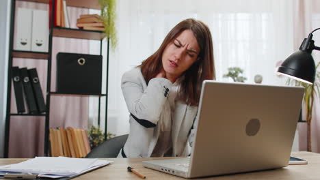 businesswoman suffers from spine neck muscle pain at home office working on laptop overworking