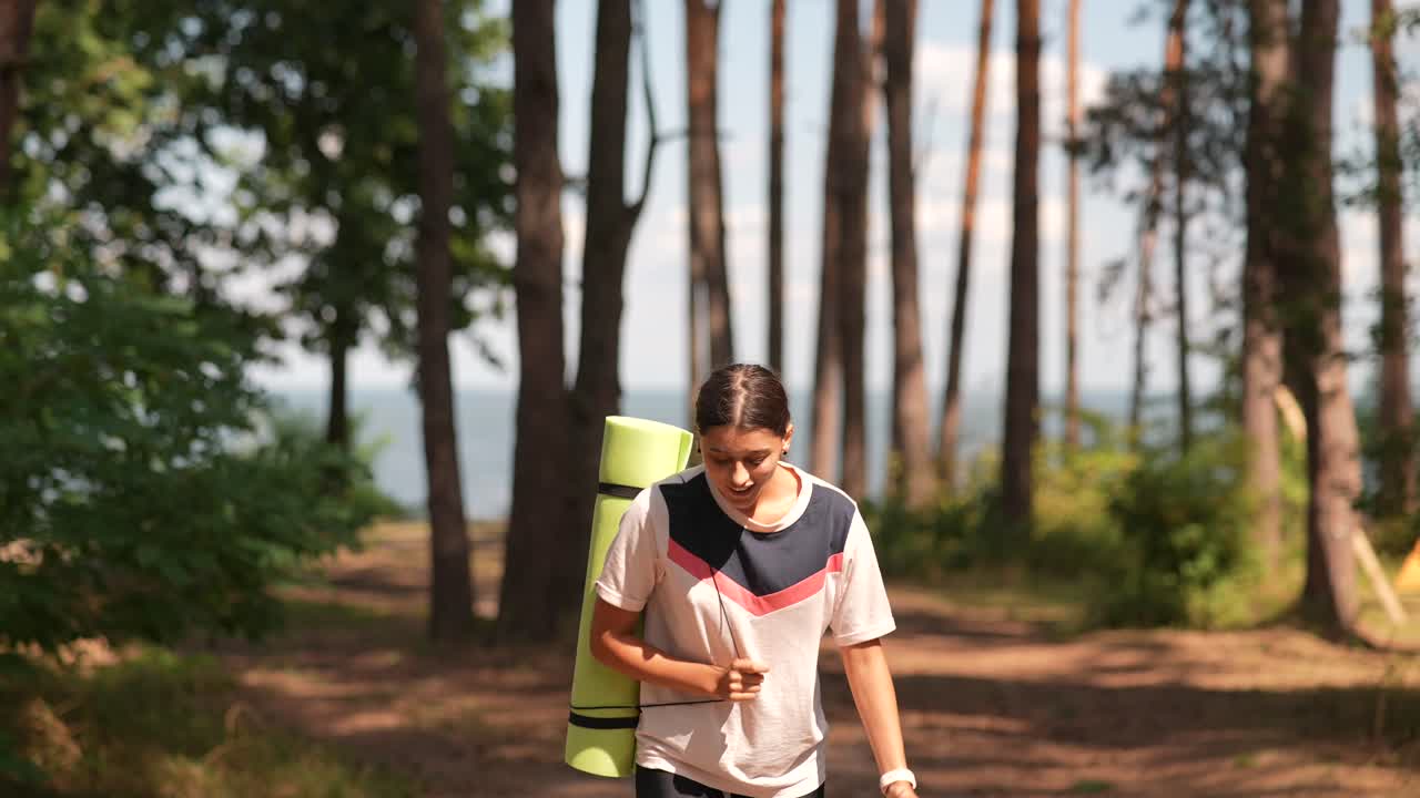 mujer llevando una alfombra de yoga en un bosque
