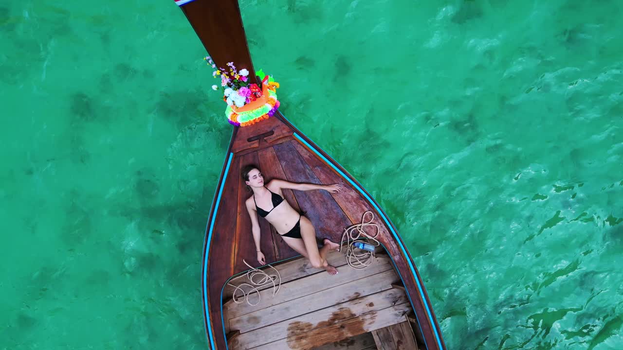 소녀는 태국 만의 롱테일 보트에 누워 있습니다.