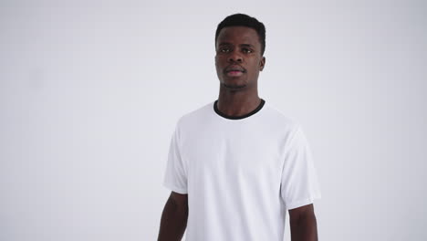 Portrait-of-an-African-ethnic-footballer-in-a-white-uniform-on-a-white-background-walking-and-looking-at-the-camera-the-camera-moves-back-from-the-headshot-to-the-main-plan