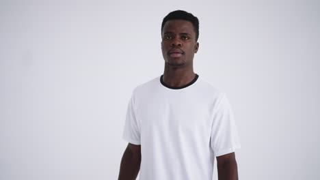 portrait of an african ethnic footballer in a white uniform on a white background walking and looking at the camera the camera moves back from the headshot to the main plan