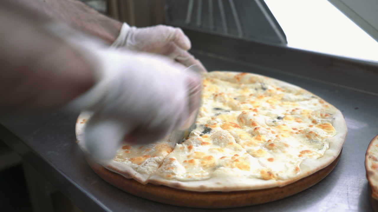 Cutting pizza on slices with special knife. Hand holding knife.