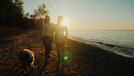 Paar-Geht-Bei-Sonnenuntergang-Mit-Einem-Hund-Spazieren