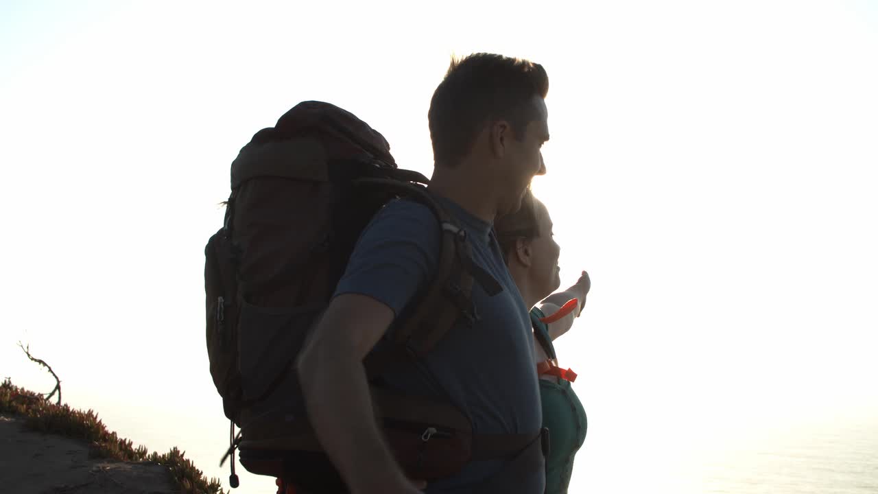 Uçurumda duran sırt çantalı, heyecanlı turist çifti.