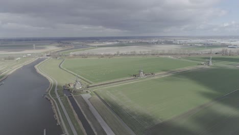 high aerial drone shot of a dutch landscape with windmills on farmland with river