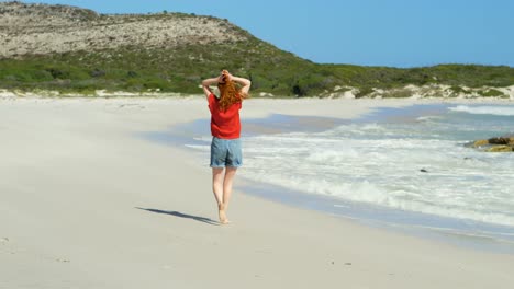 mujer caminando por la playa en un día soleado 4k