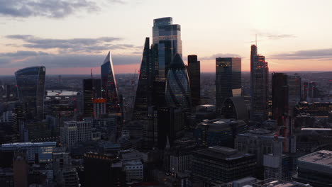 Slide-and-pan-elevated-footage-of-group-of-modern-tall-office-buildings-in-City-financial-district.-View-against-twilight-sky.-London,-UK