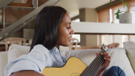 Frau-Mit-Gemischter-Abstammung-Sitzt-Zu-Hause-Auf-Der-Couch-Und-Spielt-Gitarre-Und-Singt