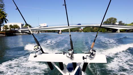 boat moving under bridge with fishing rods