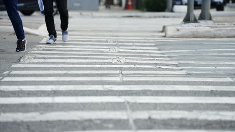 pedestrians crossing a street by the crosswalk of a big city in daylight filmed in super slow motion in 4k high definition