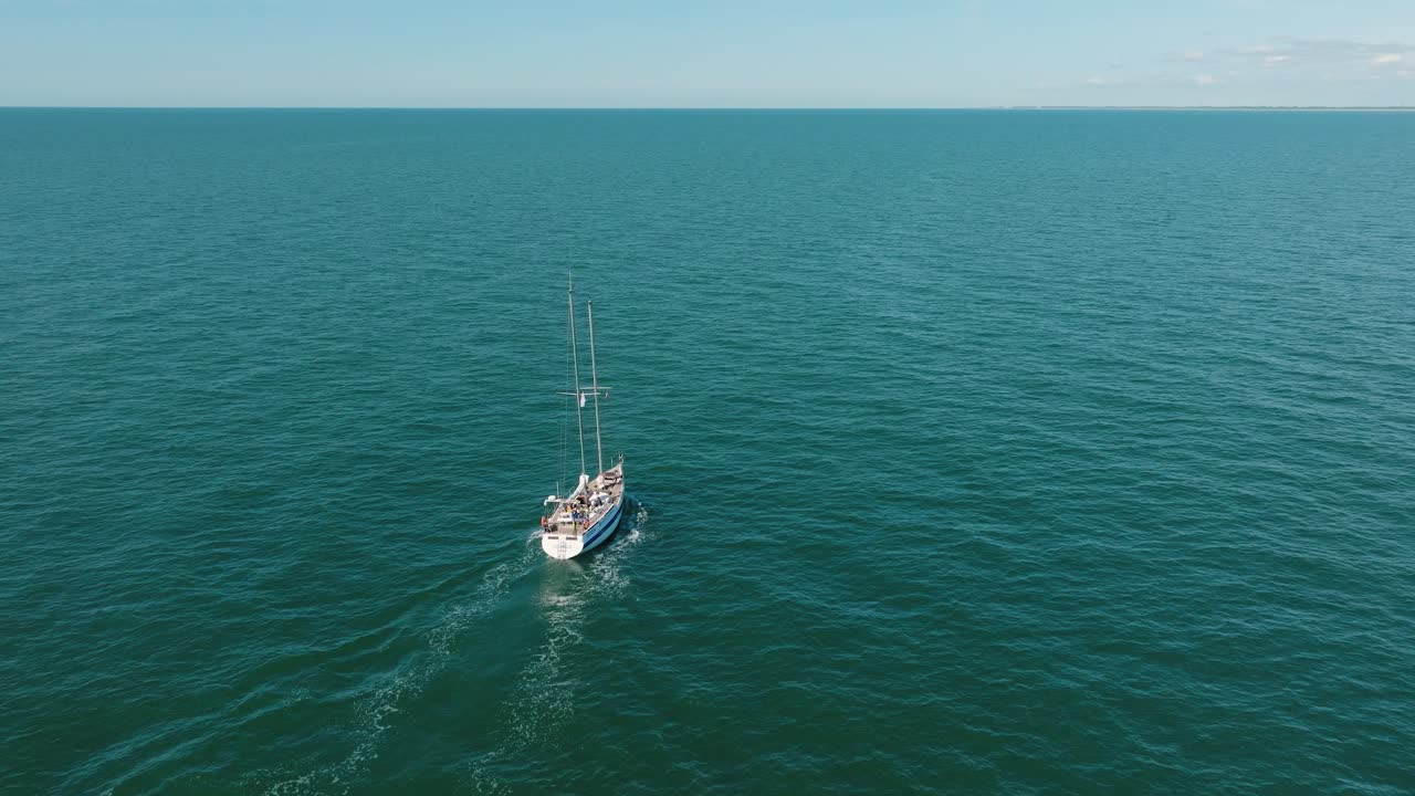 vista aérea de un velero blanco en el tranquilo mar báltico, yate de vela blanco en medio del mar sin límites, día soleado de verano, disparo amplio avanzando, inclinándose hacia abajo