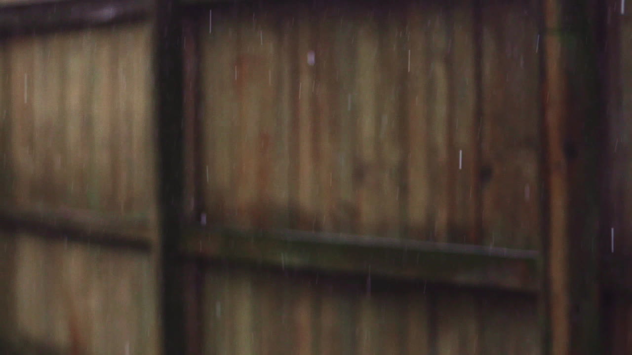 Pioggia costante cade davanti a una recinzione di legno - Super slow motion