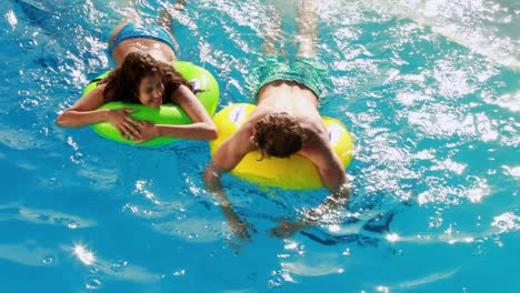 Pareja-Nadando-En-Anillos-Inflables-En-La-Piscina