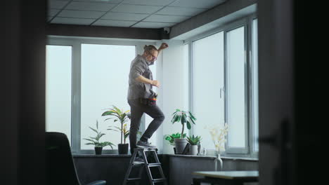 man installing window treatments