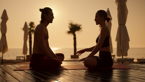 a girl and a guy sit on the red carpet and communicate during a golden sunrise on the beach near the sea. communication after