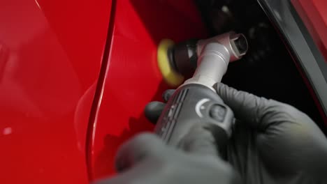 mechanic worker hands polishing a car with polishing machine - close up