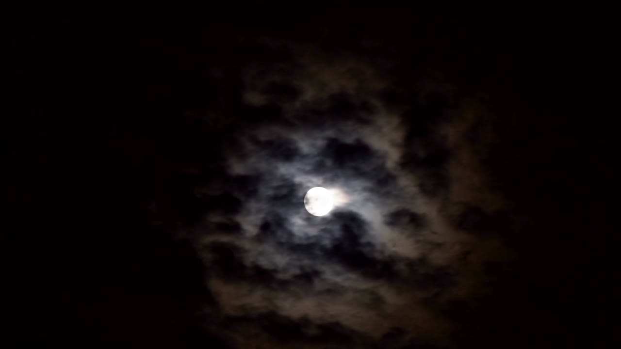 Cielo notturno misterioso con nuvole e luna piena.