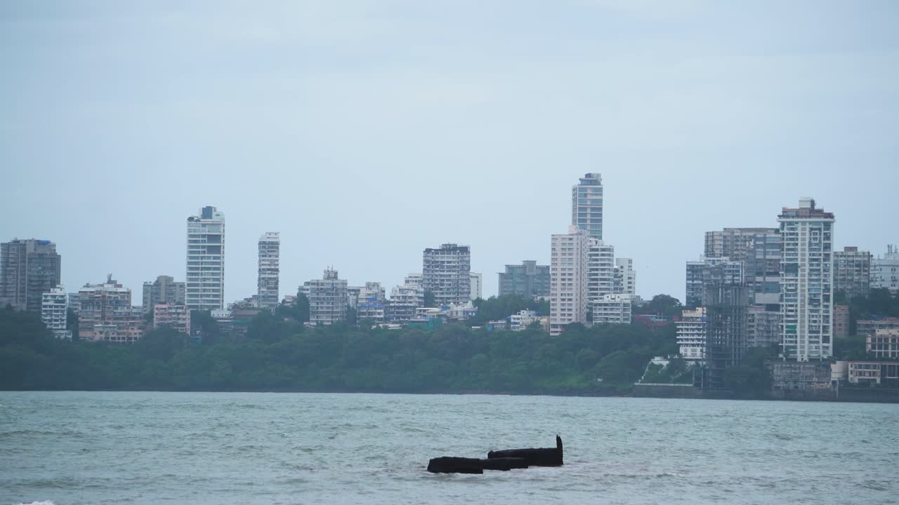 Pan shot of skyline buildings of Mumbai with ocean in front on a cloudy monsoon day