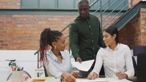 Happy-diverse-female-and-male-business-colleagues-discussing-work-at-office