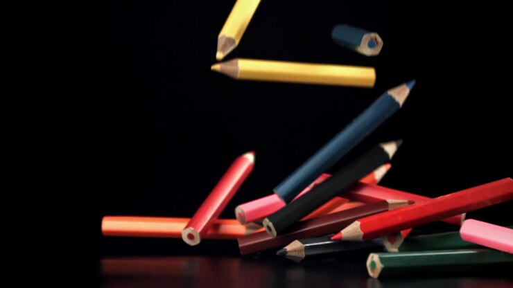 Vibrant Colored Pencils Falling in Slow Motion on Black Background