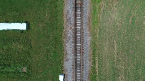 An-Aerial-Head-On-Above-View-of-a-Steam-Passenger-Train-Approaching,-Traveling-Thru-Harvested-Farmlands-on-a-Sunny-Day-in-Slow-Motion