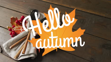 animation of hello autumn text over cutlery and autumn leaves over wooden background