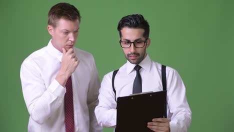 dos jóvenes empresarios multiétnicos trabajando juntos contra un fondo verde