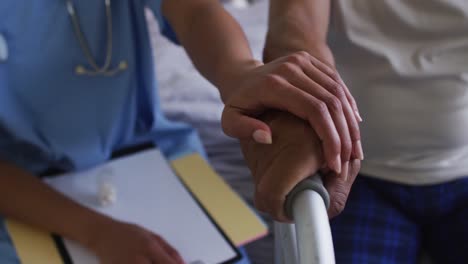 primer plano de un hombre de raza mixta con una doctora visitando la casa tomados de la mano