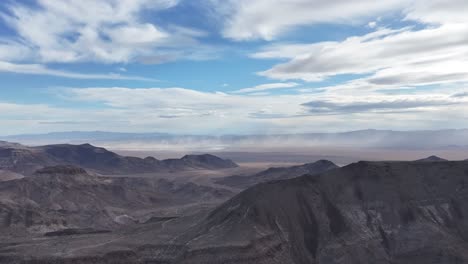 drone strafes right over nevada desert mountains with parallax and dust storm in distance. el dorado dry lake visible under dramatic clouds. ideal for scenic or establishing shots.