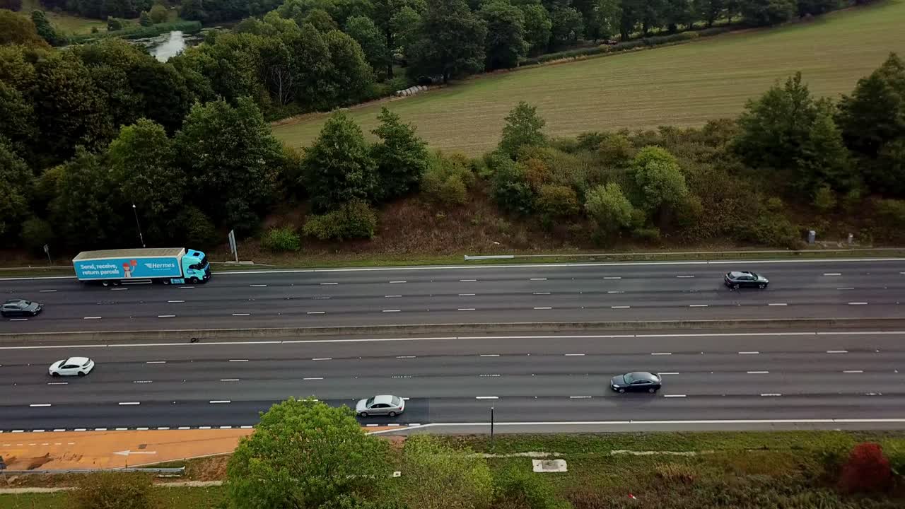 Drone above M1 Motorway with light traffic flying sidways left to right with emergency breakdown area