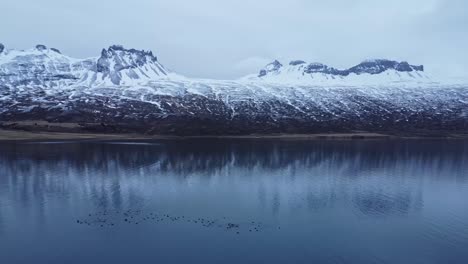 snowy rocky mountains at lakeside on winter day