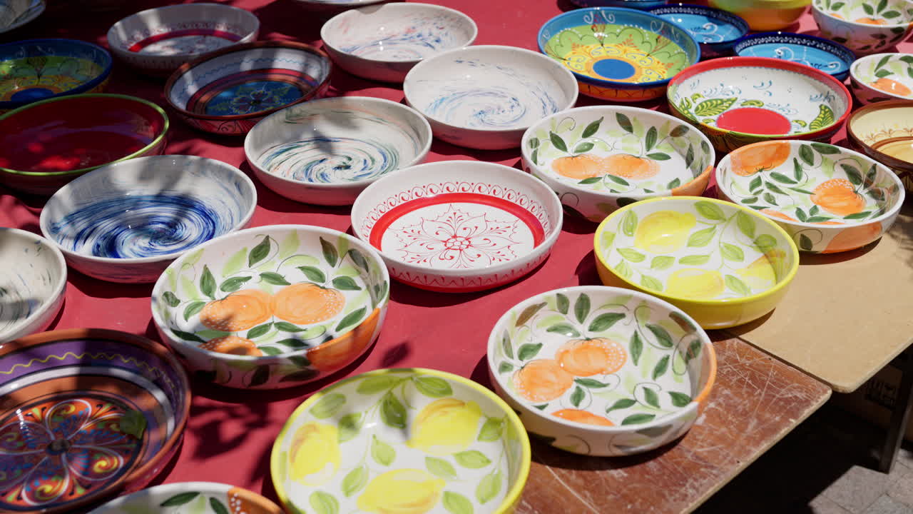 Valencia, Spain - May 21, 2025: Stacks of hand painted mini bowls neatly arranged on a stall table in soft daylight