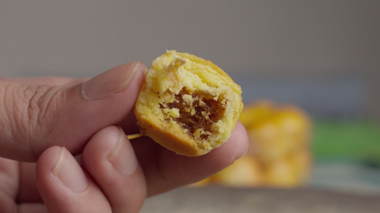 Una mano tiene un nastar con un morso, un delizioso biscotto indonesiano ripieno all'ananas