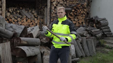 Lumberjack-in-reflective-jacket.-Man-woodcutter-with-big-axe.-Sawn-logs,-firewood-background