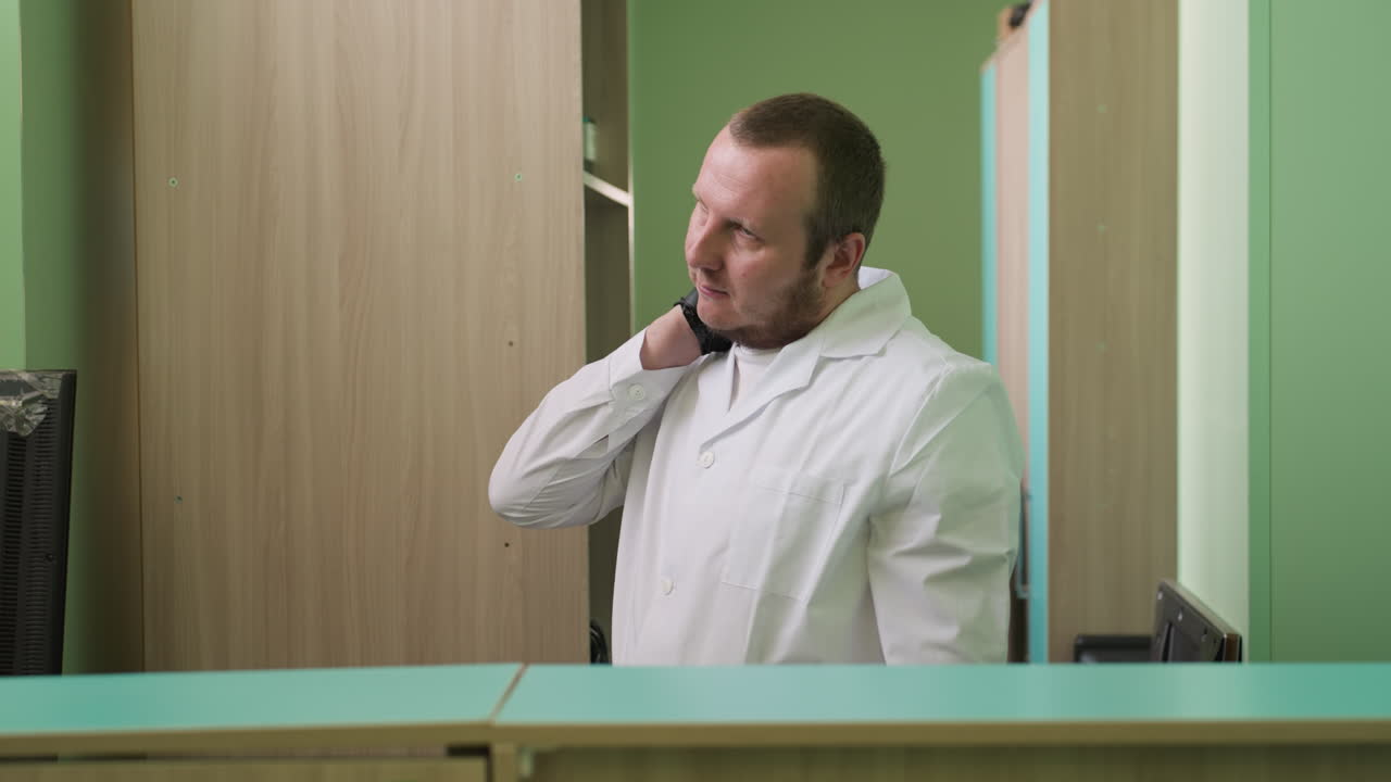 색 코트와 검은색 손수건을 입은 실험실 기술자가 오른손으로 목을 문지르고 목을 휘두르는 측면