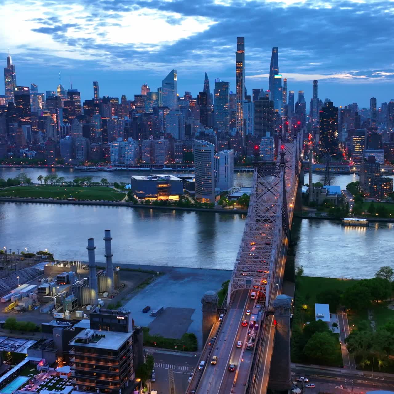 Evening falling on the beautiful New York. Queensboro Bridge over the river. Never sleeping city switching on lights. Aerial view
