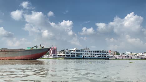 panning shot along the busy river port in dhaka with cargo ship passing