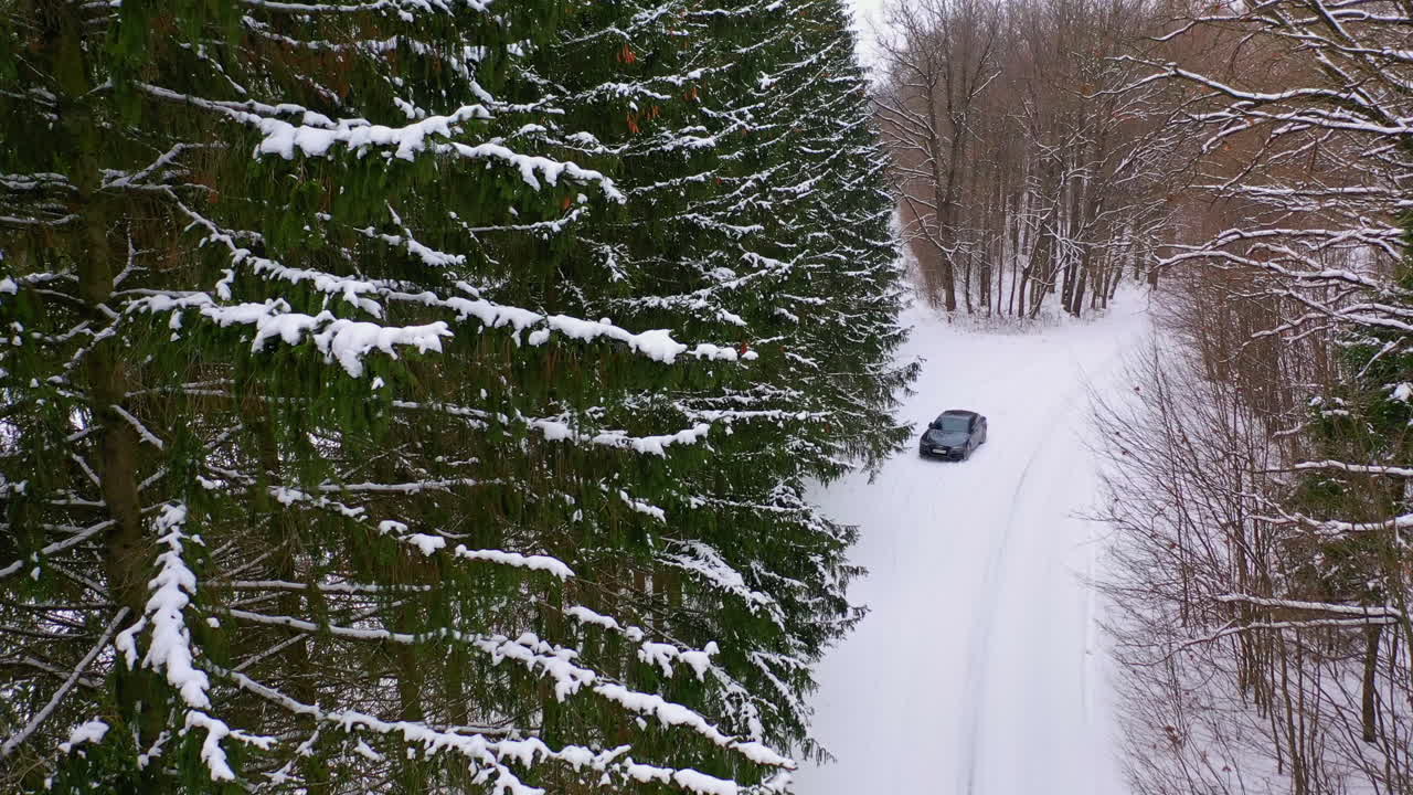 Drone view of car on winter road. Aerial shot of snow covered road in the countryside with car on way