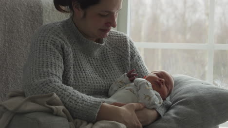 Madre-Sosteniendo-Al-Bebé-Recién-Nacido-El-Primer-Día-En-Casa,-Mira-Al-Bebé-Con-Afecto