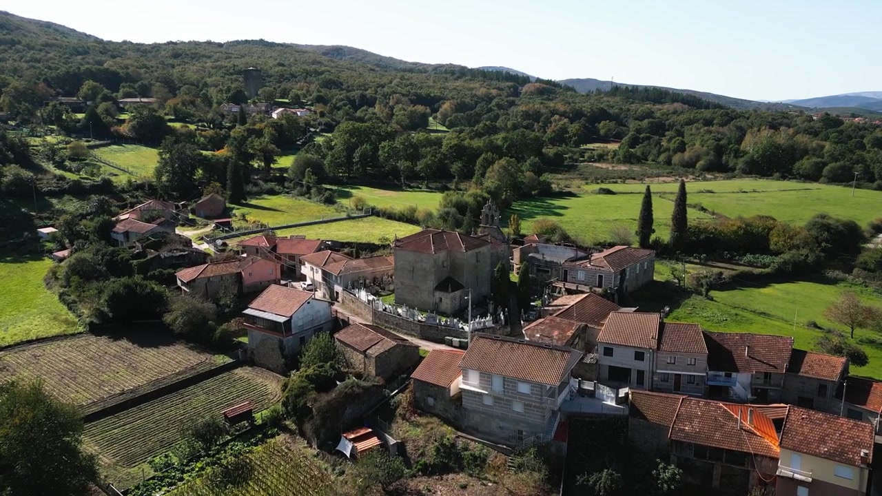 Chiesa di Santa Maria de Porqueira tra le case del villaggio a Ourense, Galizia, Spagna, panoramica aerea.