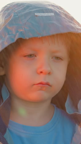 niño busca calor en la tormenta contra la luz del sol. niño triste se mantiene firme como símbolo de desafío contra las injusticias del mundo a pesar de las duras condiciones