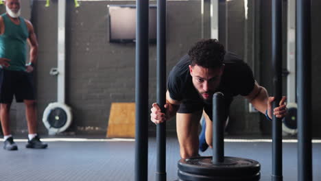 man performing sled push exercise in a gym