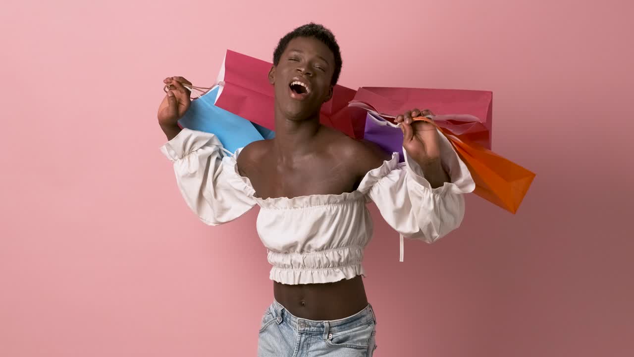 Excited African American transgender person carrying colorful shopping bags