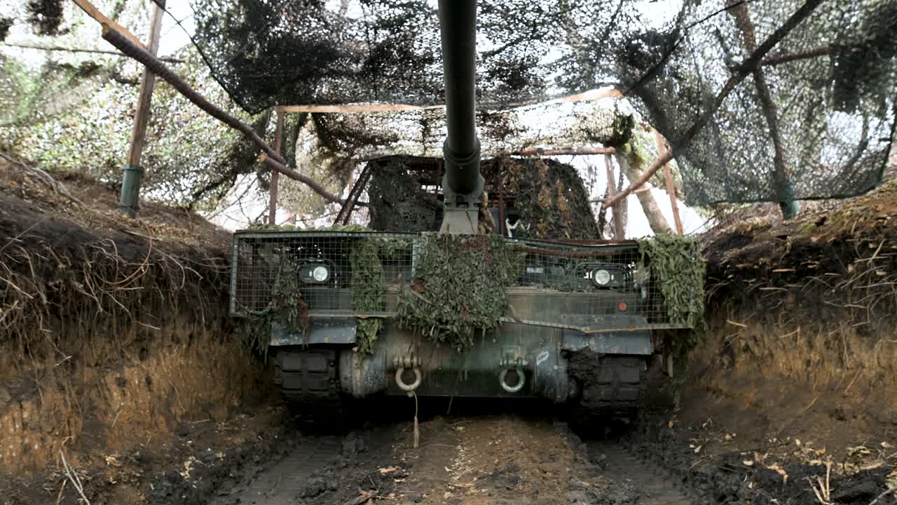 Una ripresa con movimento dall'alto verso il basso, che inizia dalla volata di un obice PzH 2000, rivela l'intero pezzo d'artiglieria nascosto in una posizione di tiro fortificata sul fronte ucraino