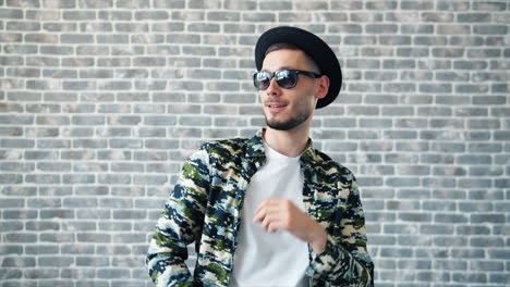 stylish man dancing in front of brick wall